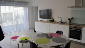 Eine moderne Küche mit Flachbildfernseher, Backofen und Essbereich mit rundem Tisch und bunten Stühlen.