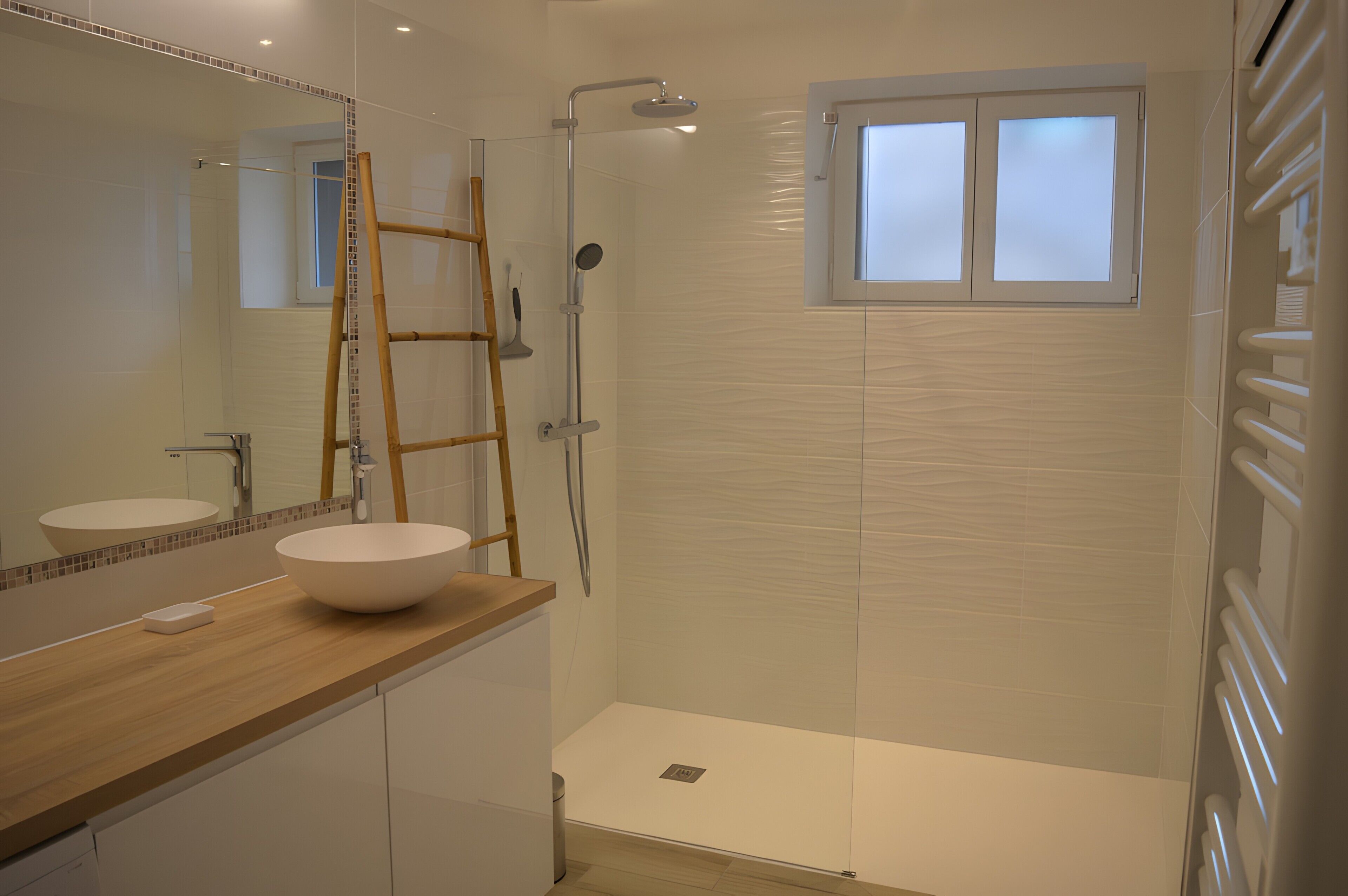 Un baño moderno con un espejo grande, un tocador de madera, un lavamanos blanco, cabina de ducha con mampara de vidrio y una ventana.