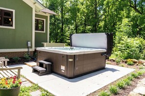 A hot tub in a garden setting with a house in the background.