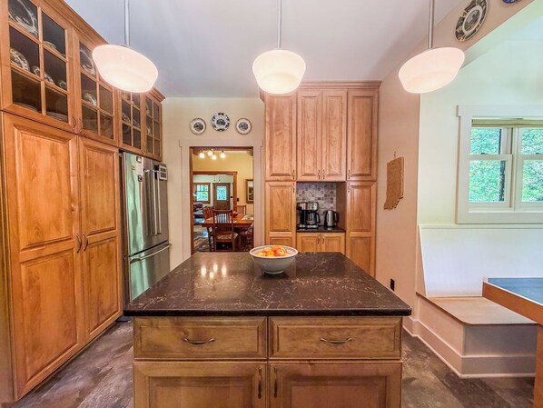 A kitchen with wooden cabinets, a marble countertop, and pendant lighting.