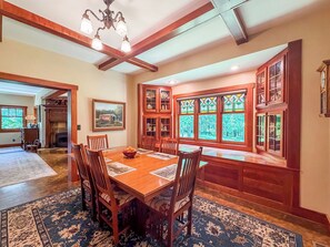 A dining area with a wooden table, chairs, and a large window with stained glass.