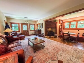 A cozy living room with a fireplace, leather sofa, wooden coffee table, and a dining area with a table and chairs.