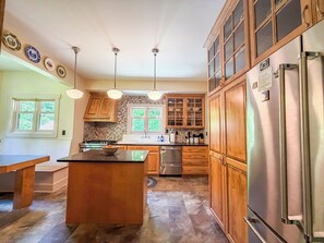 A kitchen with wooden cabinets, a stainless steel refrigerator, and pendant lights.