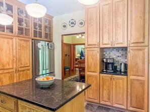 Una cocina con armarios de madera, un refrigerador de acero inoxidable, un bol de fruta en la encimera y una cafetera.