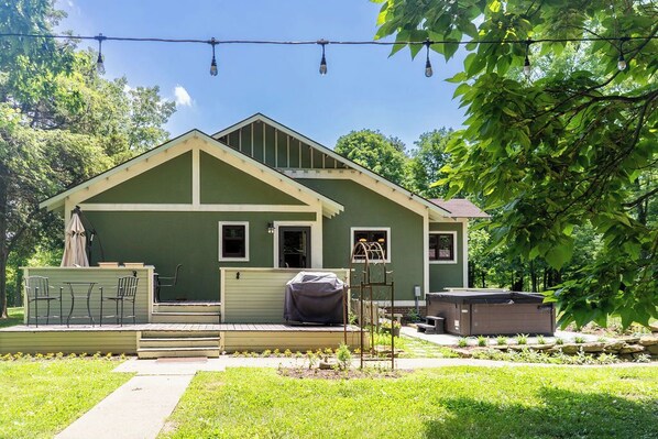A house with a covered patio, a hot tub, and a small garden.