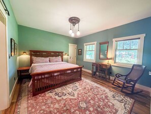 Un dormitorio con cama de madera, escritorio, silla y ventana grande.