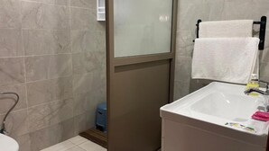 Un baño con inodoro, lavabo, cabina de ducha de vidrio y barra para toallas.