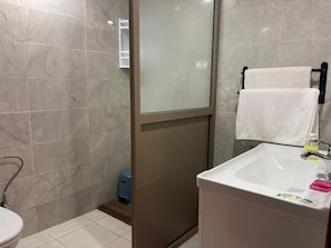A bathroom with a toilet, a sink, a glass shower enclosure, and a towel rack. - TAMOUNT Surf House (Agadir)