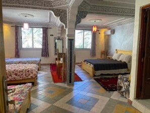 A room with two beds, a wooden chair, a red mat, and a patterned wall. - TAMOUNT Surf House (Agadir)