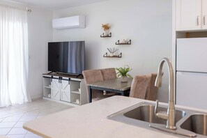 A modern kitchen with a built-in stove, a sink, and a dining area with a table and chairs. - Grace Bay Condo with Pool and Patio Near Beach (Grace Bay)