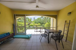 Ein Zimmer mit Balkon, Tisch mit Stühlen, einem Bett und einem Deckenventilator.