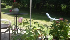 A garden patio with a table, chairs, and potted plants.