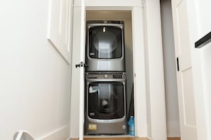 Eine kompakte Waschmaschine und ein Trockner in einem schmalen Flur.
