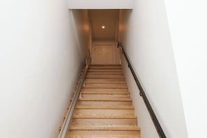 A wooden staircase with a handrail, leading to a door at the top.