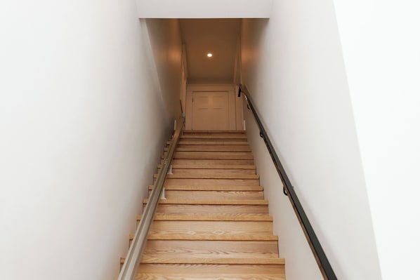 Una escalera de madera con barandilla que lleva a una puerta en la parte superior.