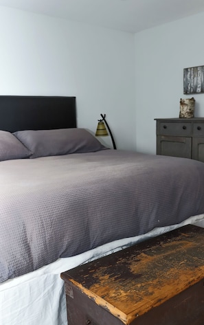 A bed with a headboard, a bedside table, and a dresser with a mirror.