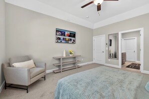 A bedroom with a bed, a chair, a TV on the wall, and a door leading to another room. - New ranch 4 bedrooms w pool table, Nascar (Harrisburg)