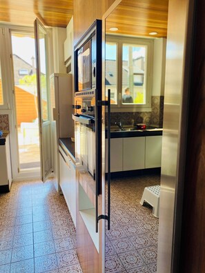 Una cocina moderna con horno empotrado, refrigerador y ventana con vista al patio trasero.
