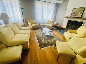Una sala de estar con un sofá, sillones, una mesa de centro y una alfombra.