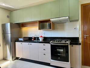 Eine kleine Küche mit Edelstahl-Kühlschrank, Mikrowelle, Herd und Spüle.