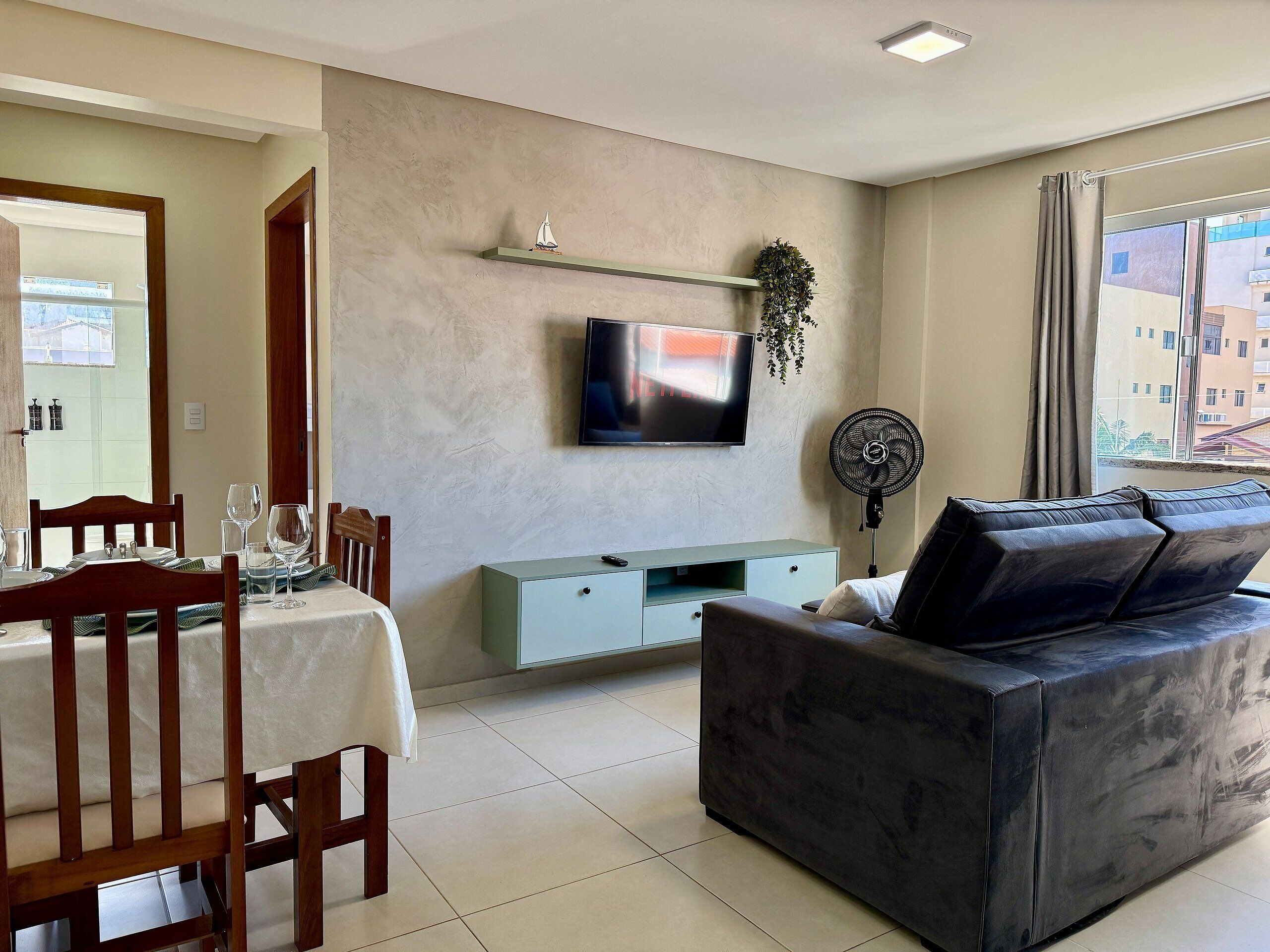 Un salon moderne comprenant un coin repas, un téléviseur à écran plat fixé au mur, un canapé et une table à manger avec des chaises.