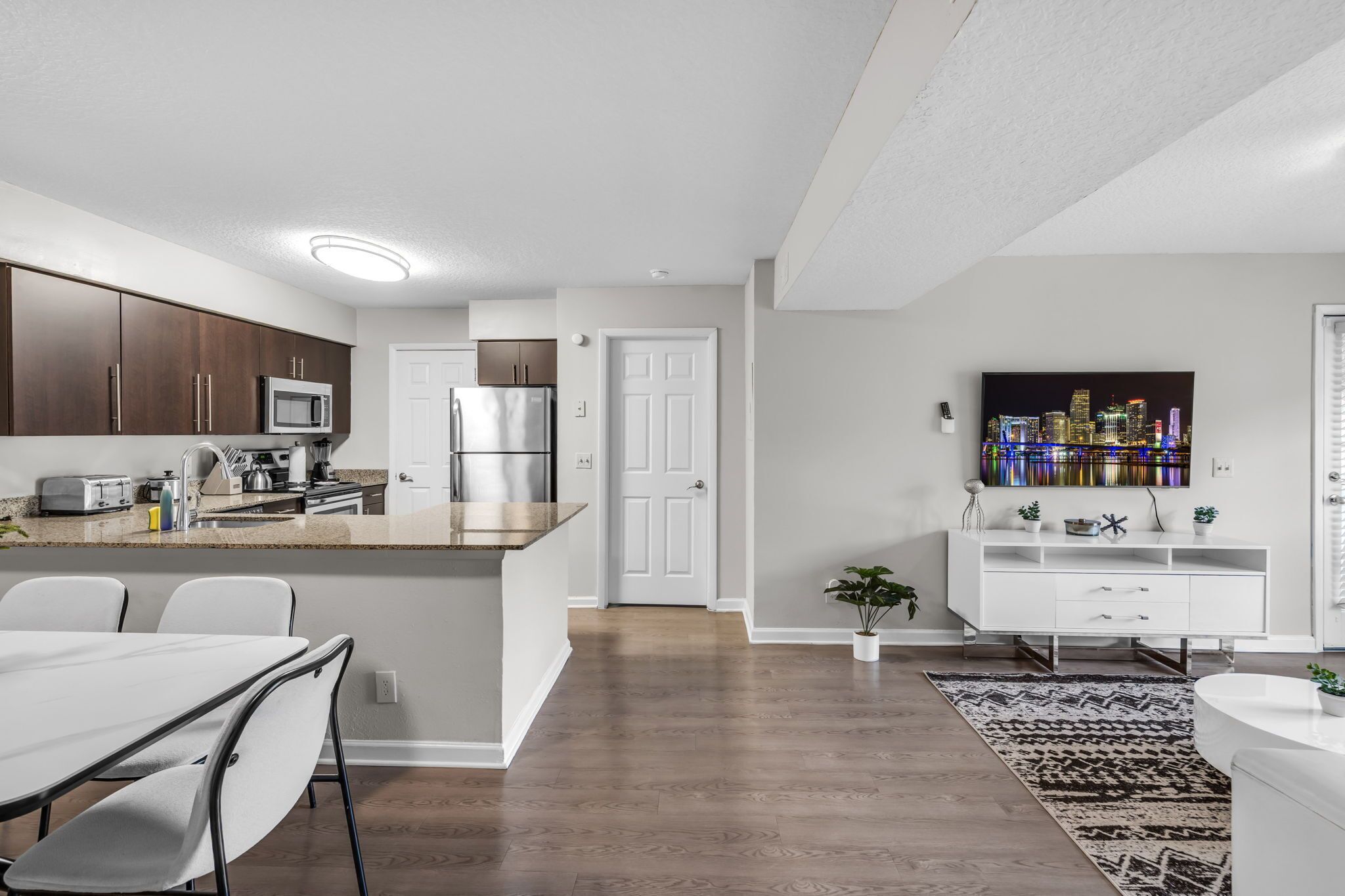 A modern kitchen with dark wood cabinets, stainless steel appliances, and a white countertop.