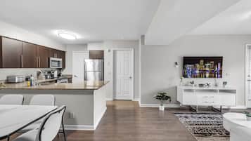 A modern kitchen with dark wood cabinets, stainless steel appliances, and a white countertop.