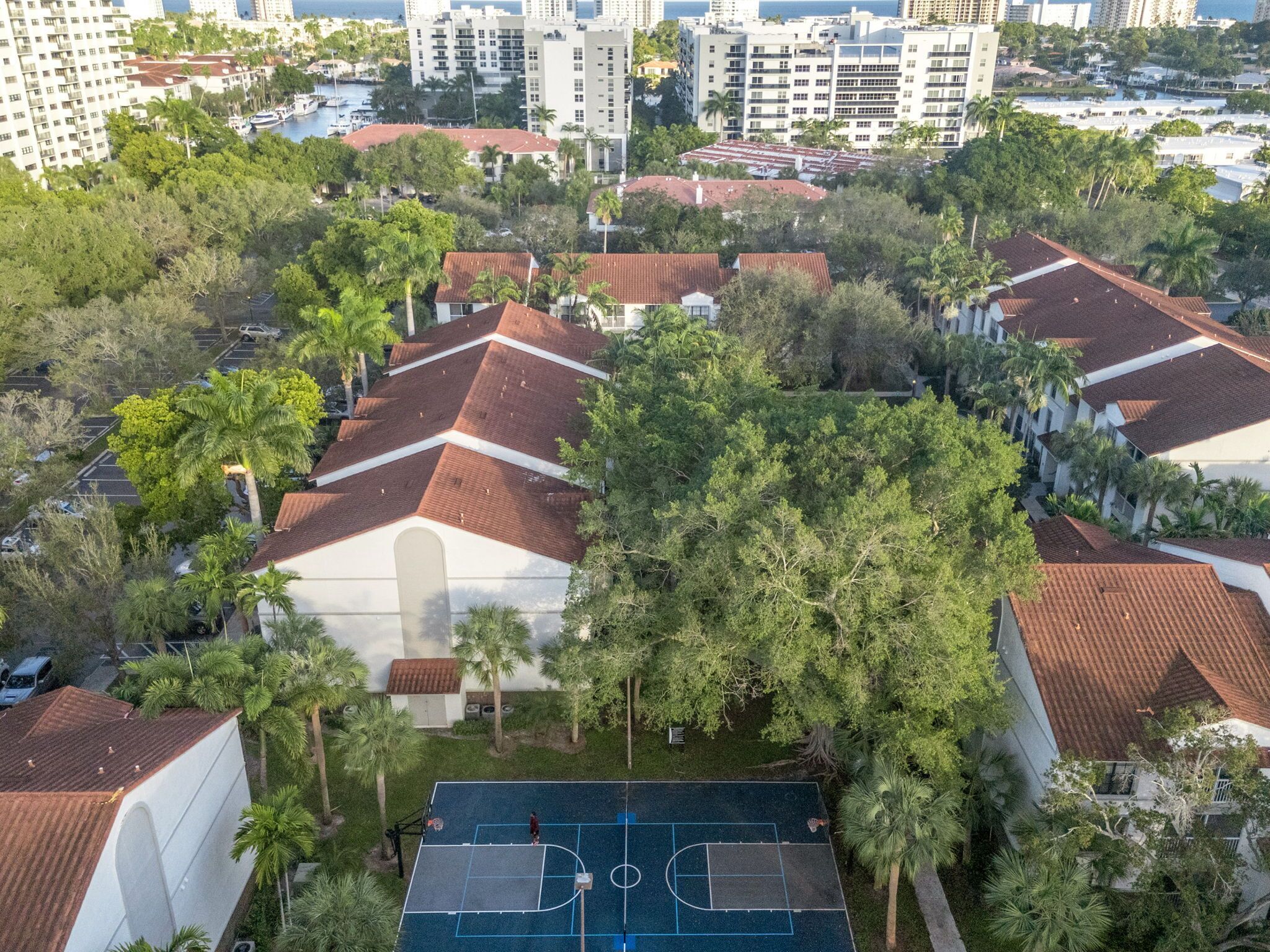 A residential area with multiple buildings, a basketball court, and surrounding greenery.