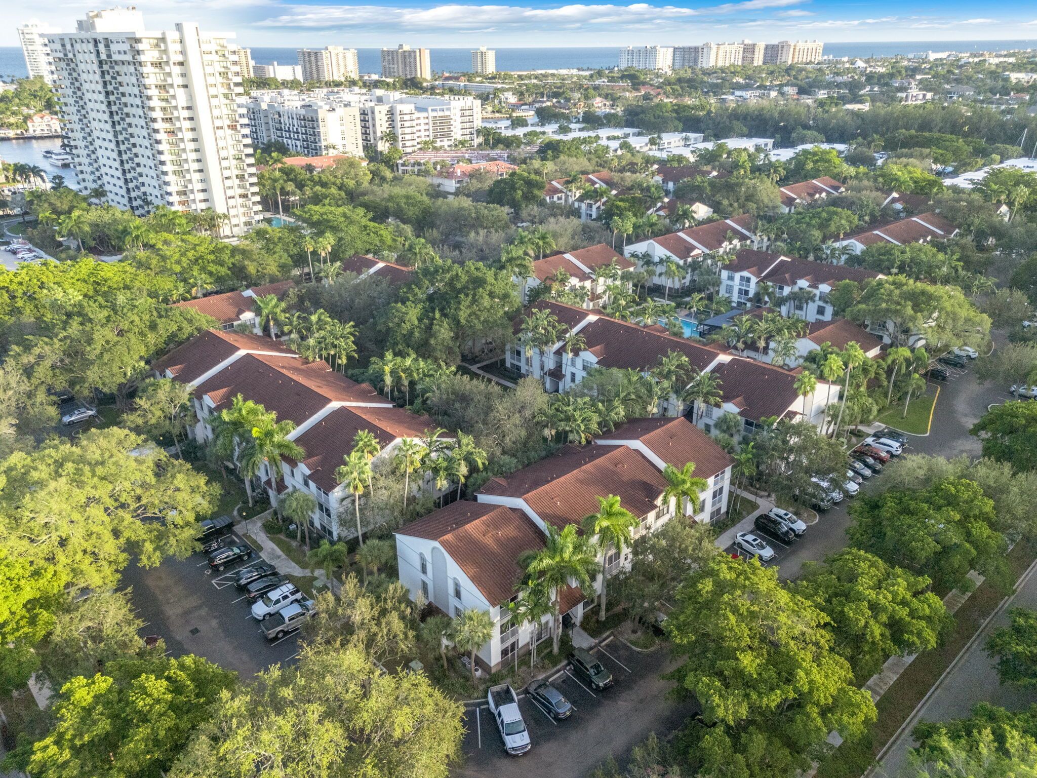 A residential area with multiple two-story buildings, each with a red-tiled roof and surrounded by greenery.