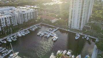 An aerial view of a marina with boats docked, surrounded by residential buildings and a large white high-rise building.