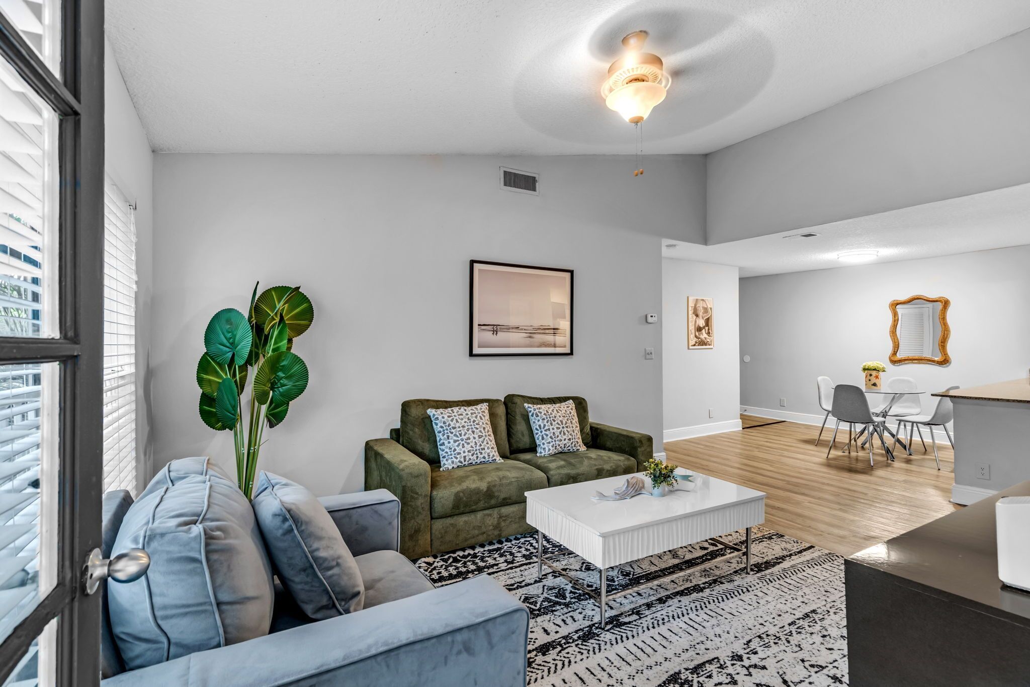 A modern living room with a sofa, coffee table, and a large plant.