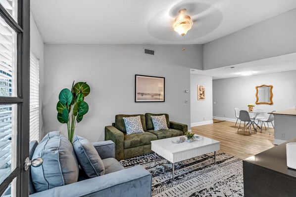 A modern living room with a sofa, coffee table, and a large plant.