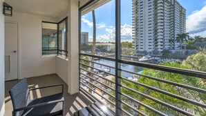 A balcony with a view of a tall building, a door, and a chair. - Port Royale Apartments (Fort Lauderdale)