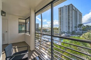 A balcony with a view of a tall building, a door, and a chair. - Port Royale Apartments (Fort Lauderdale)