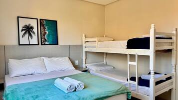 A bunk bed room with a bed, two framed pictures on the wall, and a green blanket on the bed.