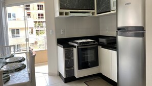 A modern kitchen with a gas stove, a built-in oven, and a stainless steel refrigerator. - 287.203 - AP Aurora: Affordable, cozy and just steps from the beach (Bombinhas)