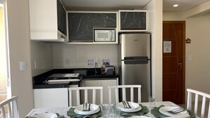 A modern kitchen with white cabinets, a black marble backsplash, and stainless steel appliances. - 287.203 - AP Aurora: Affordable, cozy and just steps from the beach (Bombinhas)