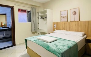 Una camera d'albergo con un letto, un armadio, un bagno e una finestra con tende.