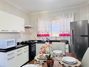 Una cocina moderna con armarios blancos, un refrigerador de acero inoxidable y un comedor listo para disfrutar de una comida.