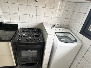 A kitchen with a gas stove and a front-loading washing machine. - 09 | Res. 305 • Beautiful Apartment – Great Value, 5 Min from the Beach (Bombinhas)