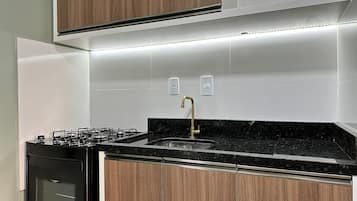 Una cocina moderna con estufa a gas, encimera negra y armarios de madera.