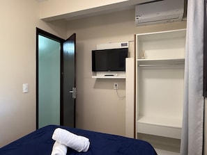 Ein Hotelzimmer mit Bett, Wandfernseher, Kleiderschrank und Klimaanlage.