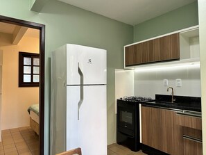Eine kleine Küche mit einem weißen Kühlschrank, einem Herd und Holzschränken.