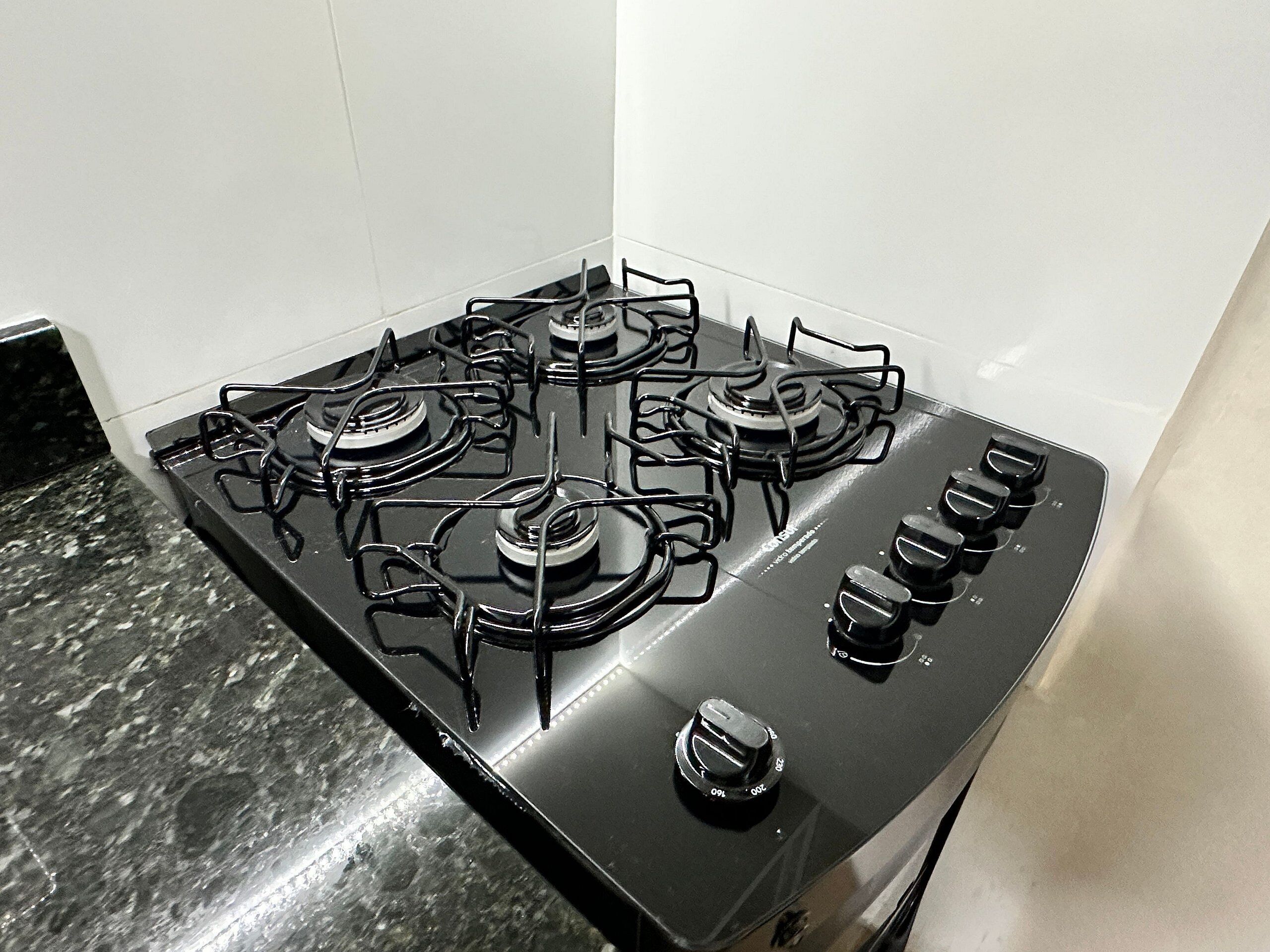 Een keuken met een zwart fornuis, vier branders en een bedieningsknop.