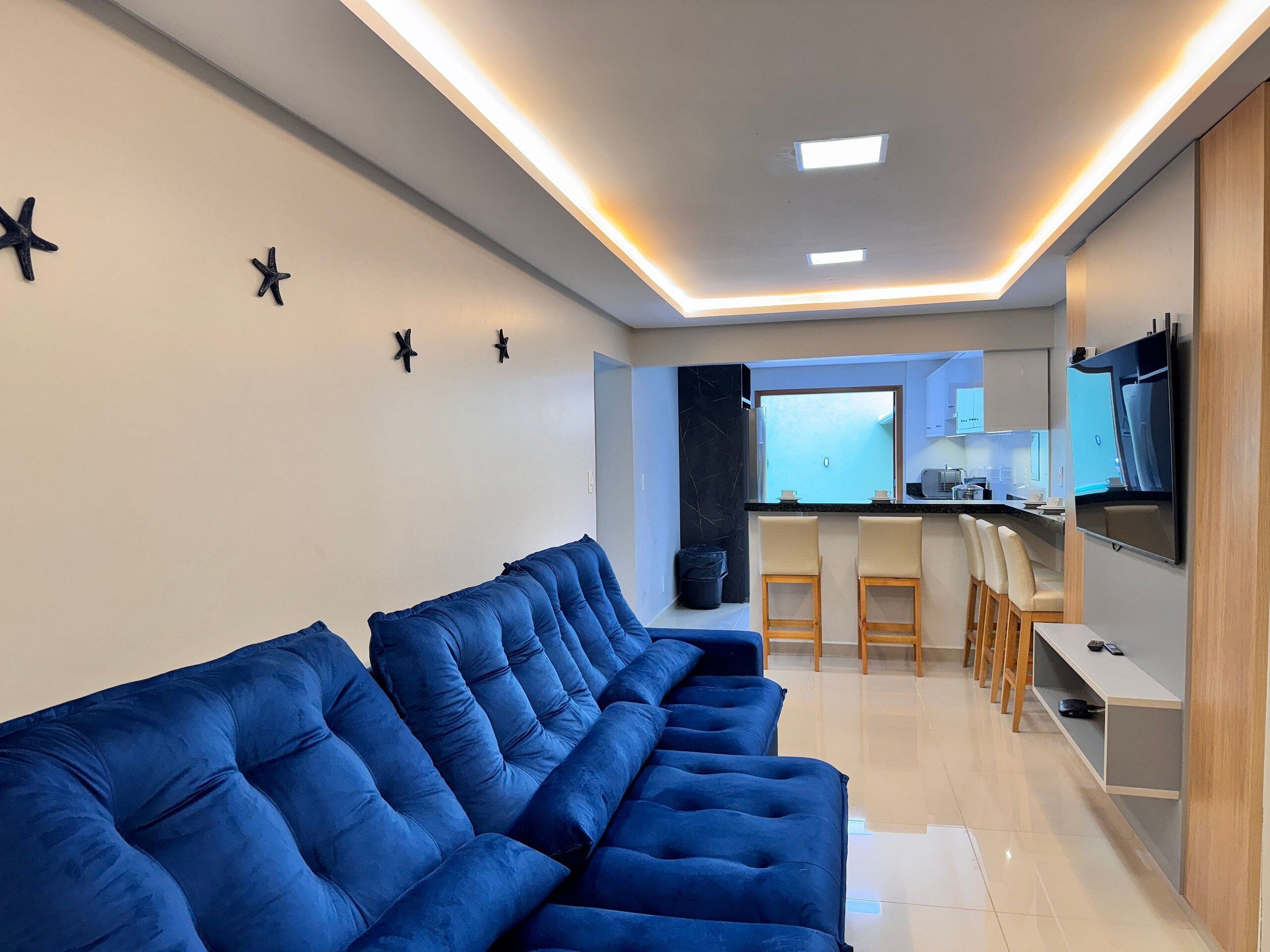 A modern living room with a sofa, a kitchen area, and a TV.