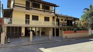 Un edificio de dos pisos con un balcón, un garaje y un muro de ladrillo.