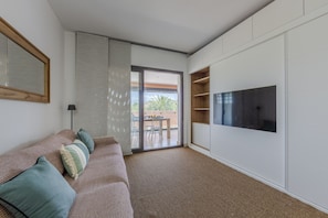 Ein modernes Wohnzimmer mit einer Couch, einem Flachbildfernseher und einer Schiebetür zu einer Außenpatio.