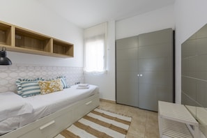 Ein Schlafzimmer mit einem Bett, einem Nachttisch, einem Kleiderschrank und einem Fenster mit Vorhängen.
