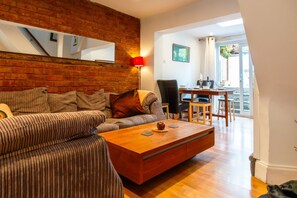 Ein Wohnzimmer mit einer Couch, einem Couchtisch, einer roten Lampe und einem Essbereich mit Tisch und Stühlen.