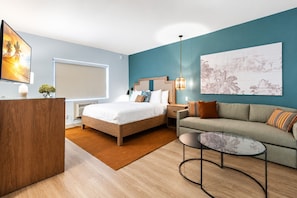 Ein modernes Hotelzimmer mit Bett, Sofa, Schreibtisch und Kunstwerken.